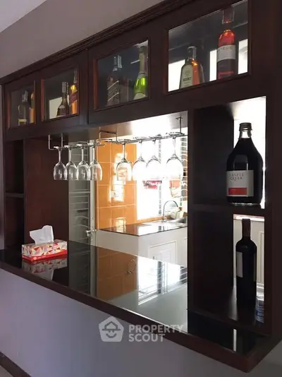 Stylish home bar with glass rack and bottle display in modern kitchen setting.