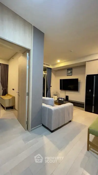 Modern living room with stylish decor and open layout, featuring a wall-mounted TV and cozy seating area.