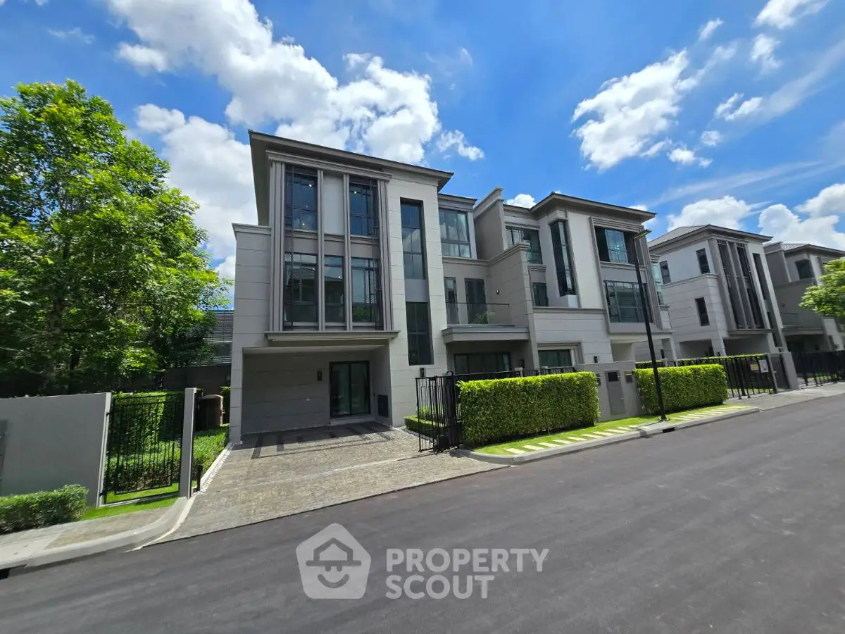 Luxurious modern townhouse with sleek design and lush greenery under a bright blue sky.