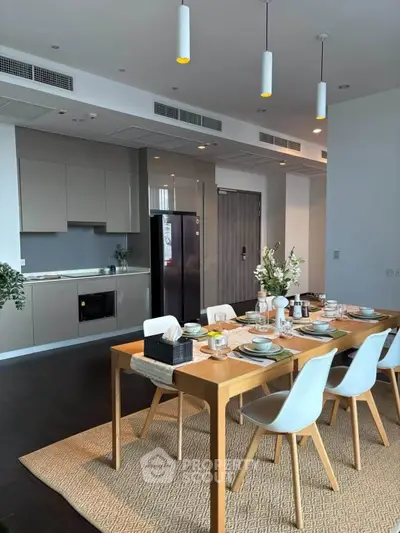 Modern dining area with elegant table setting and sleek kitchen design in open layout apartment.