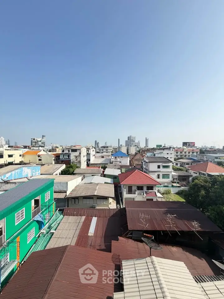 Panoramic cityscape view showcasing diverse rooftops under a clear blue sky, ideal for urban living.