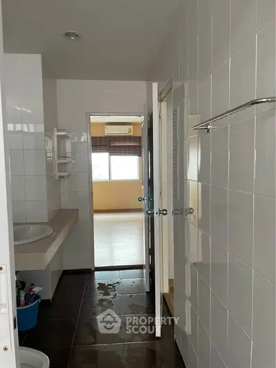 Spacious bathroom with tiled walls and modern fixtures in a bright apartment.