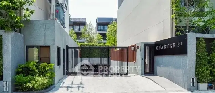 Modern gated entrance of Quarter 31 with lush greenery and contemporary design.
