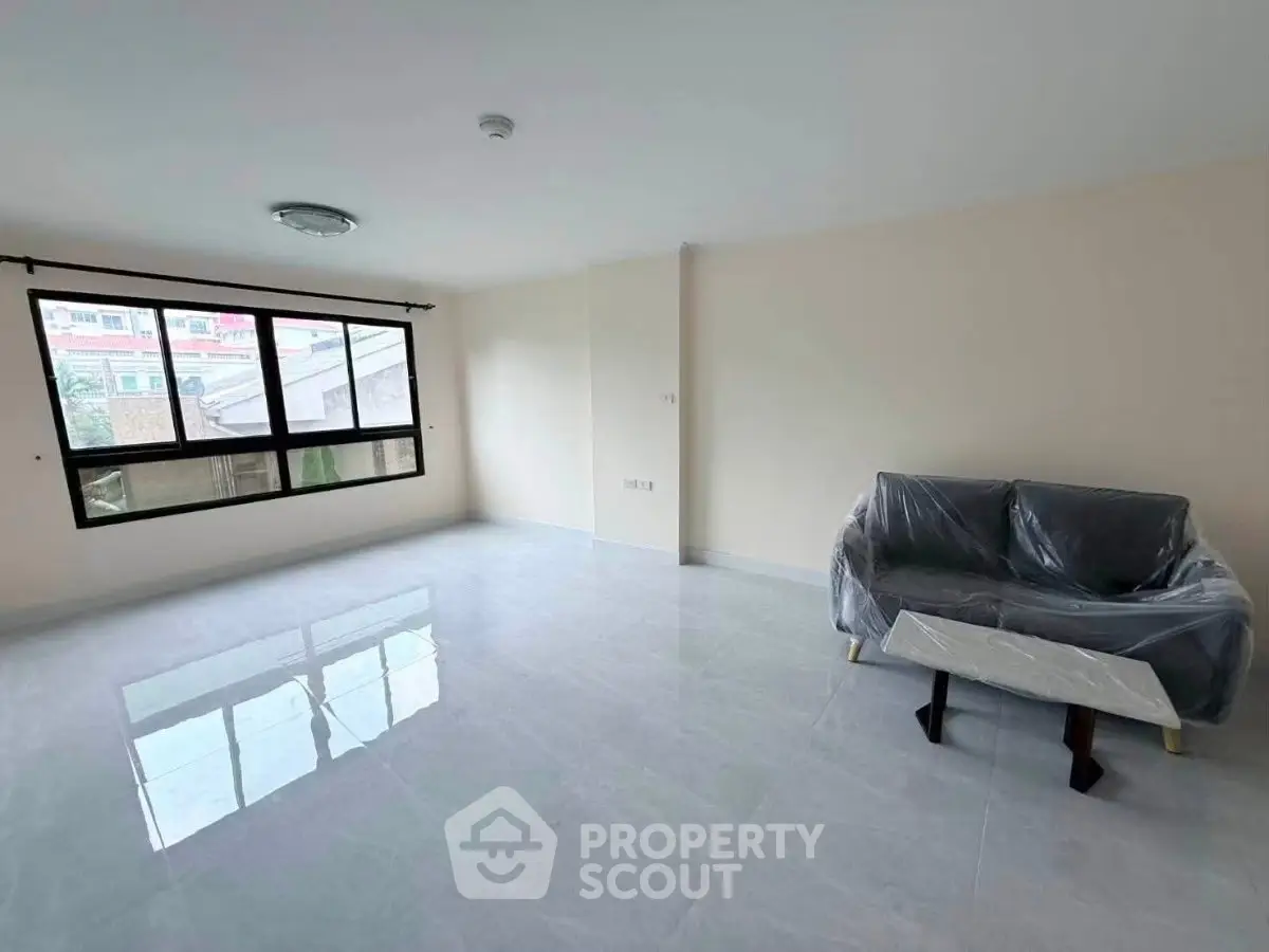 Spacious living room with large window and minimalistic furniture in modern apartment.