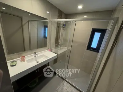 Modern bathroom with glass shower and sleek vanity in contemporary home.
