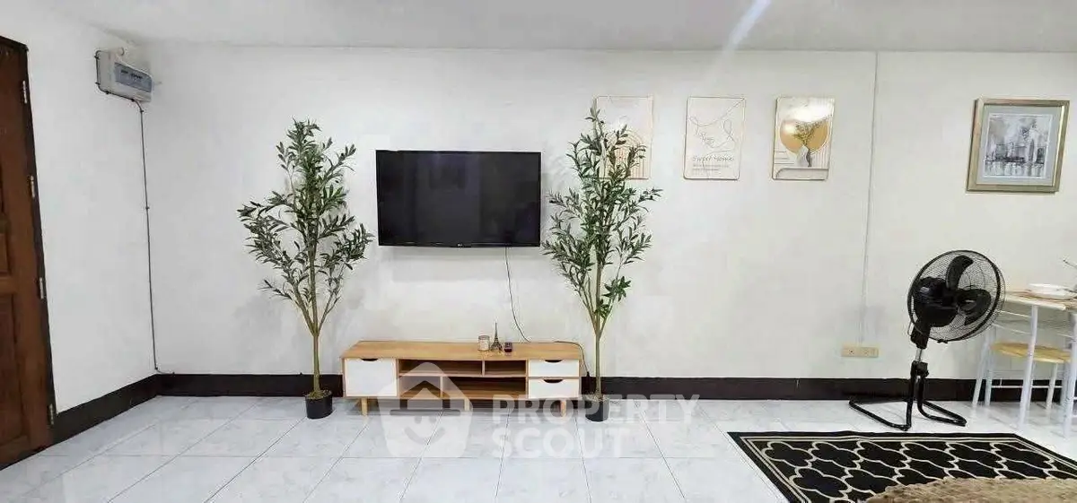 Modern living room with wall-mounted TV, stylish decor, and indoor plants for a cozy ambiance.