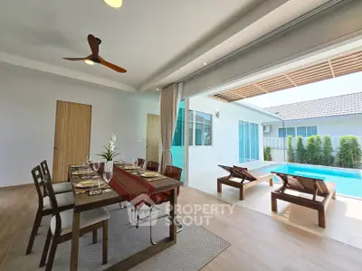 Luxurious open-plan dining area with pool view, featuring elegant table setting and modern ceiling fan.