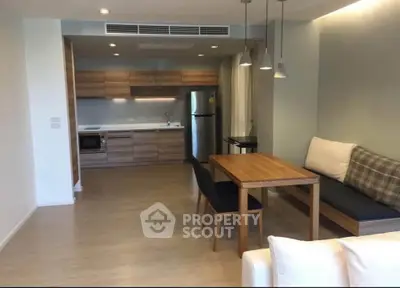 Modern open-plan living room with sleek kitchen and dining area, featuring contemporary furniture and neutral tones.