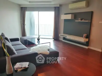 Spacious living room with polished hardwood floors, modern furniture, and abundant natural light from large balcony doors.
