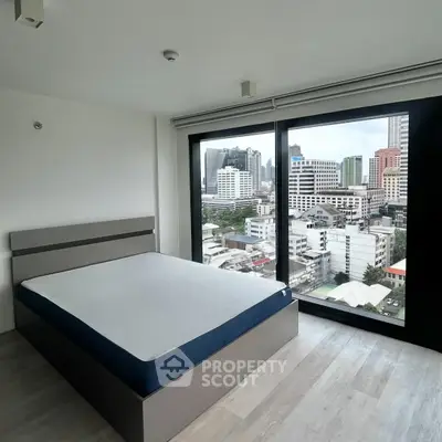 Modern bedroom with city view, featuring large windows and minimalist design.