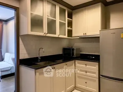 Modern kitchen with sleek black countertops and white cabinetry in a cozy apartment.