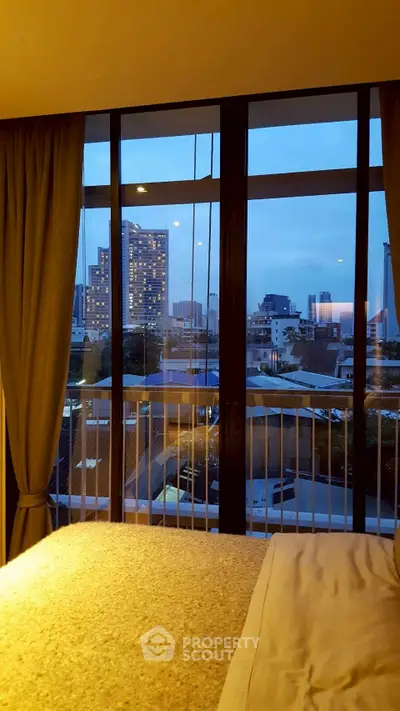 Stunning bedroom view with floor-to-ceiling windows overlooking cityscape at dusk.