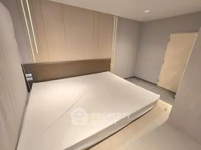 Spacious modern bedroom with minimalist design and neutral tones, featuring a large bed and sleek flooring.