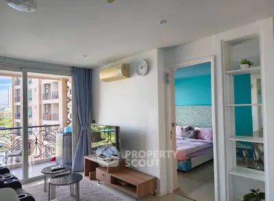 Modern living room with balcony access and view into a stylish bedroom, featuring contemporary decor and natural light.