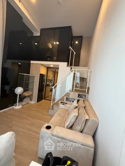 Modern loft-style living room with high ceilings and elegant staircase