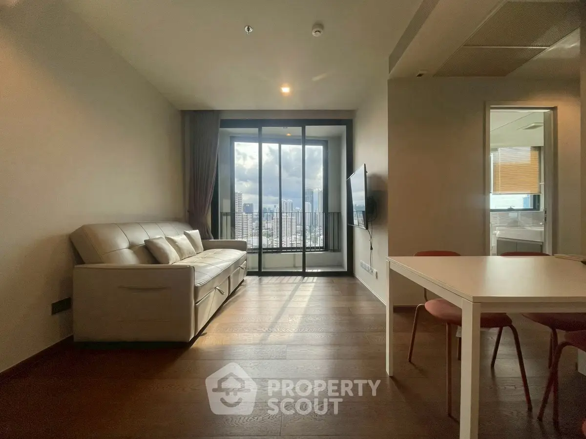 Modern living room with city view, featuring sleek furniture and natural light.