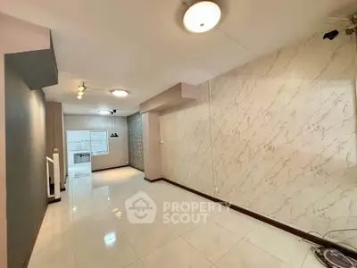 Spacious open-plan living area with modern lighting and marble accent wall
