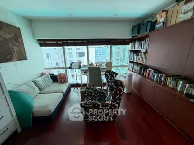 Charming living room with cozy seating and large window offering city views, perfect for relaxation and reading.