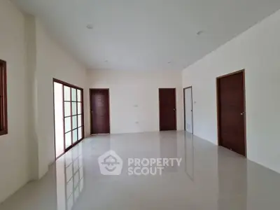 Spacious empty room with glossy tiled floor and wooden doors