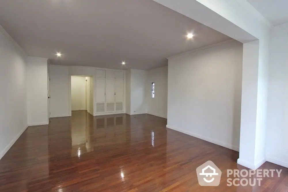 Spacious and well-lit living room with polished hardwood floors and built-in storage, perfect for modern urban living.