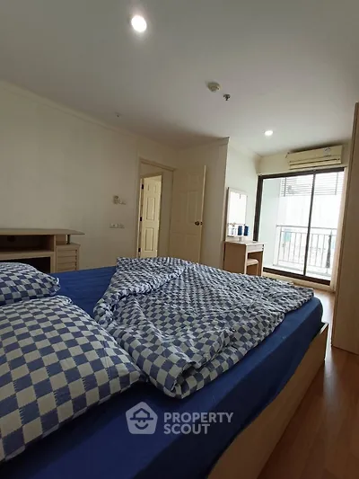 Spacious bedroom with balcony access and stylish blue checkered bedding.