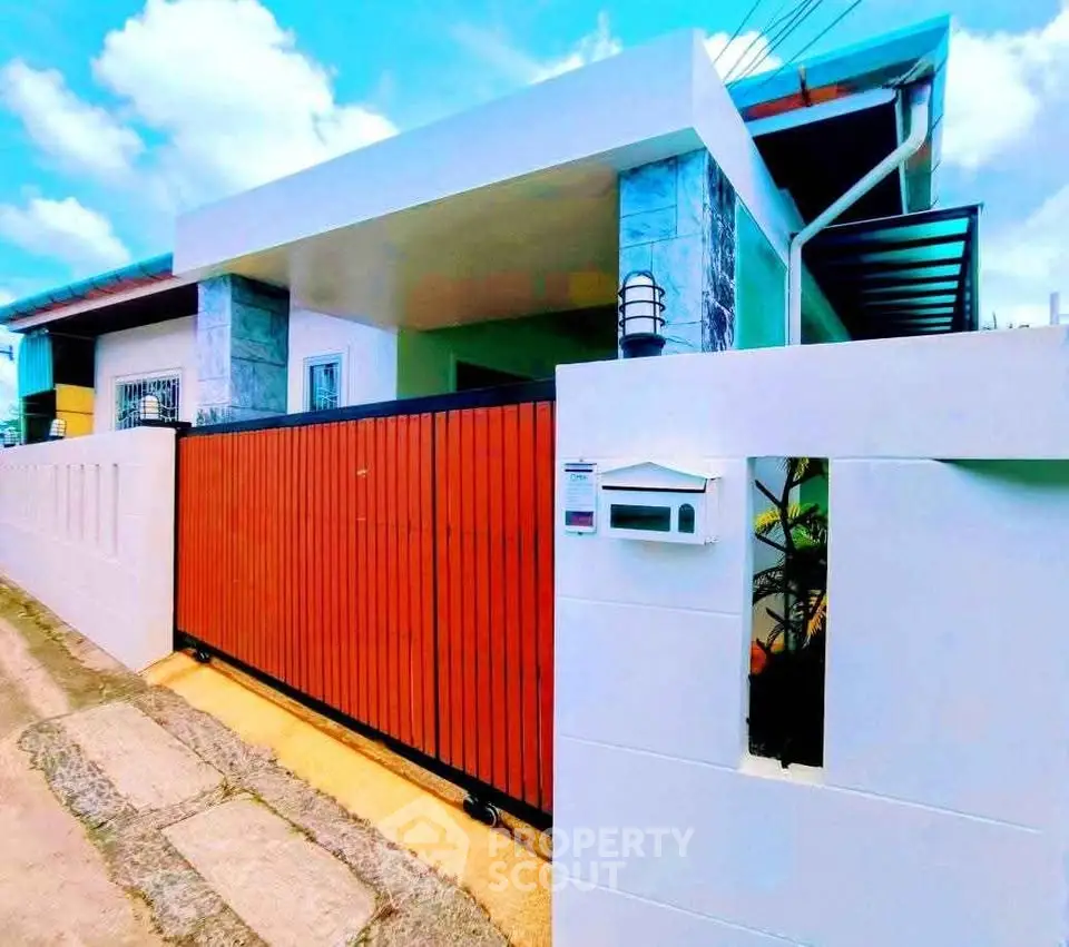 Modern single-story home with sleek design and vibrant red gate