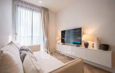 Modern living room with stylish decor and large window, featuring a sleek TV setup and cozy seating.