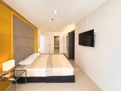 Spacious modern bedroom with wall-mounted TV and elegant decor