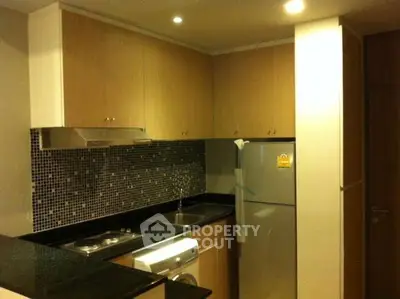 Modern kitchen with sleek cabinets, mosaic backsplash, and stainless steel appliances.