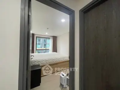 Modern bedroom with large window and minimalistic decor in urban apartment.