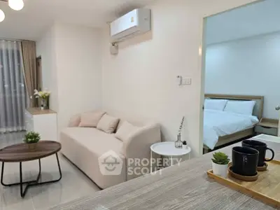 Modern open-plan living room with cozy sofa and view into a stylish bedroom, perfect for urban living.
