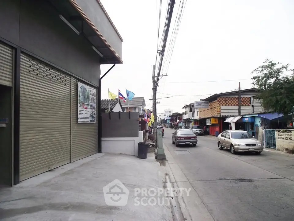 Street view of commercial area with shops and parked cars, showcasing local architecture.