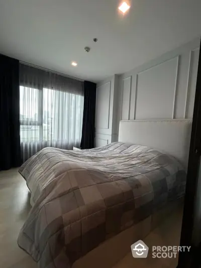 Modern bedroom with large window and stylish decor in a contemporary apartment.