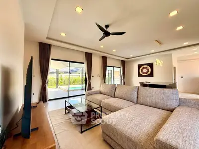 Spacious modern living room with large sectional sofa and pool view, perfect for relaxation and entertainment.