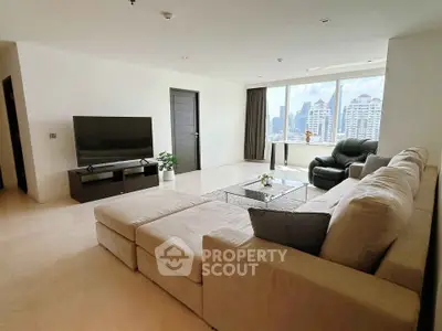 Spacious modern living room with city view, large sofa, and sleek TV setup.