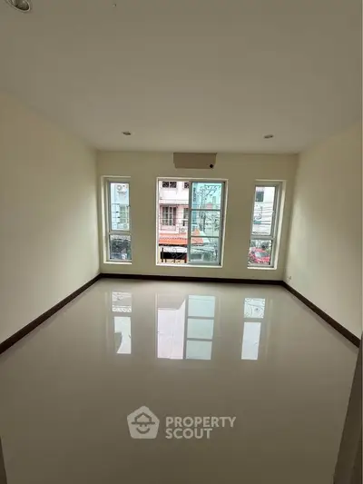 Spacious unfurnished room with large windows and glossy floor, ideal for customization.