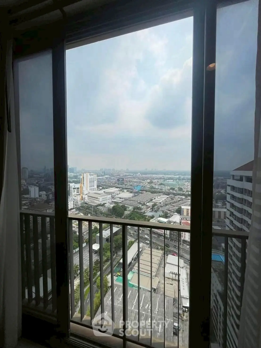Stunning urban view from high-rise apartment window with expansive cityscape.