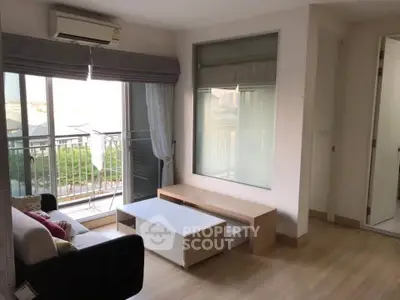 Modern living room with large windows and balcony access, featuring sleek furniture and natural light.
