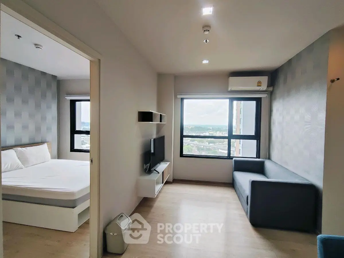 Modern apartment interior with spacious living area and bedroom, featuring large windows and stylish decor.