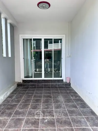 Spacious tiled balcony with sliding glass doors and natural light