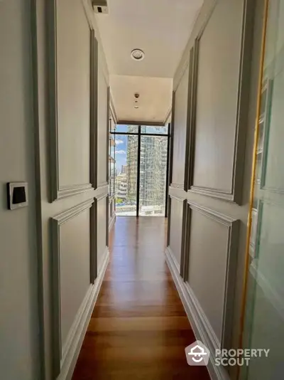 Elegant hallway with wooden flooring and city view through large windows