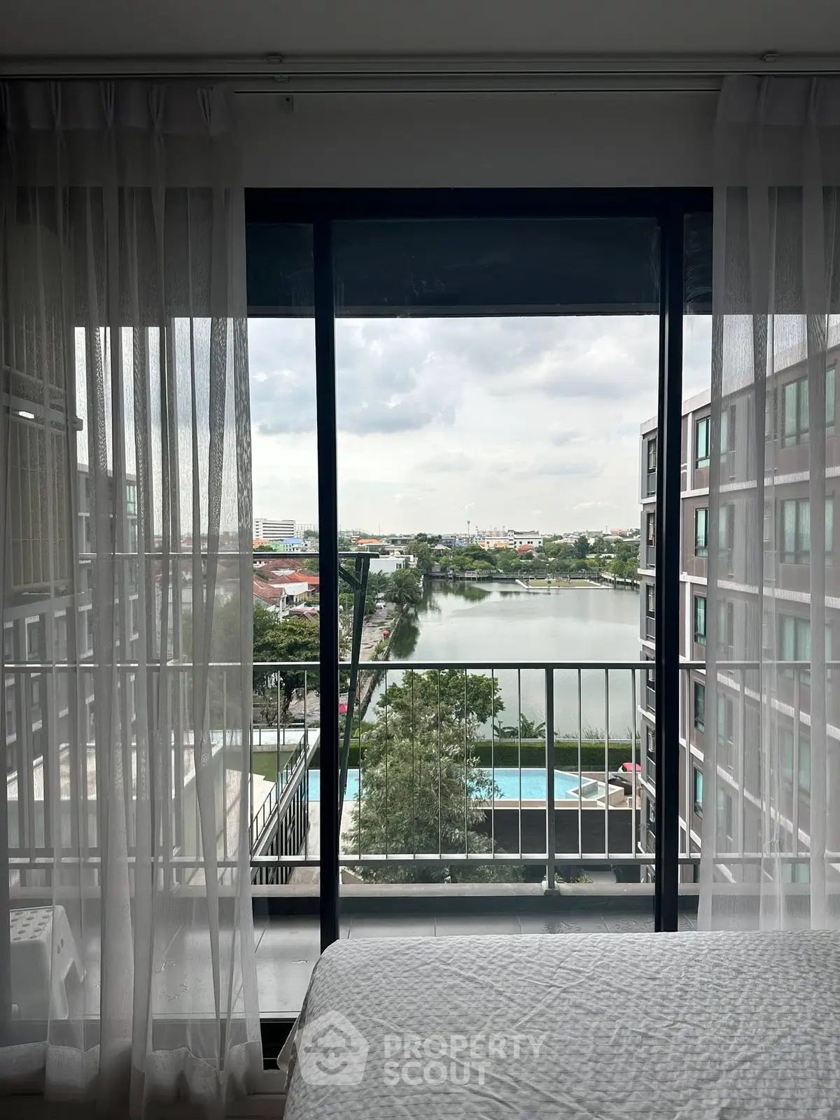 Stunning apartment view with balcony overlooking serene river and modern pool area.