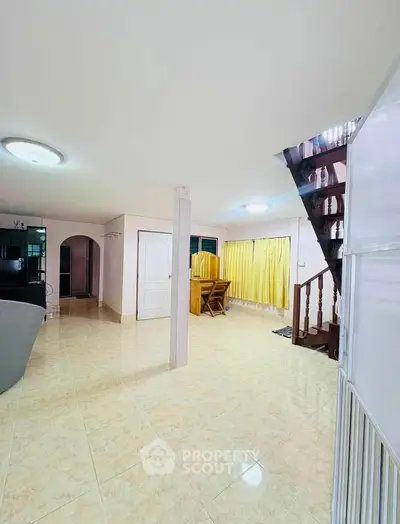 Spacious open-plan living area with staircase and tiled flooring