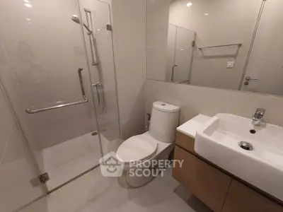 Modern bathroom with glass shower and sleek fixtures in a contemporary apartment.