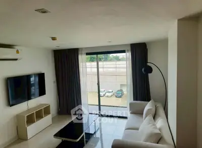 Modern living room with sleek furniture and large window offering natural light.