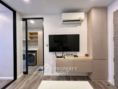 Modern living room with sleek TV setup and view into laundry area