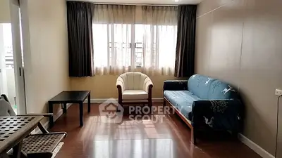 Spacious living room with natural light, modern furniture, and wooden flooring.