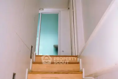 Modern staircase with wooden steps leading to a sliding glass door in a minimalist home.
