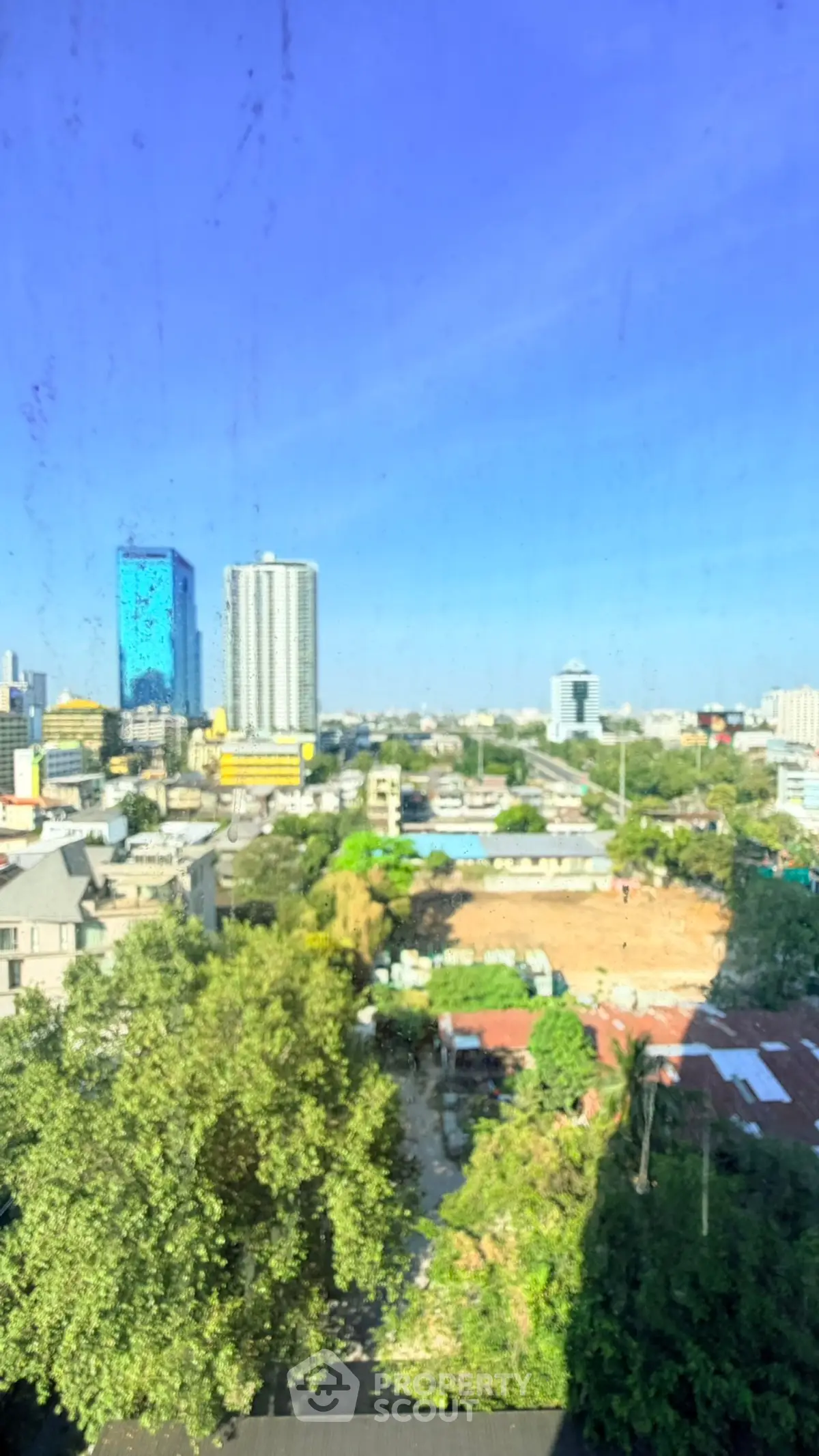 Stunning cityscape view from a high-rise building, showcasing urban skyline and greenery.