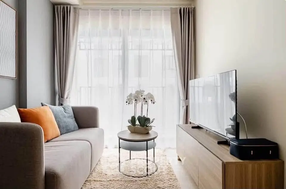 Modern living room with cozy sofa, stylish decor, and large window for natural light.
